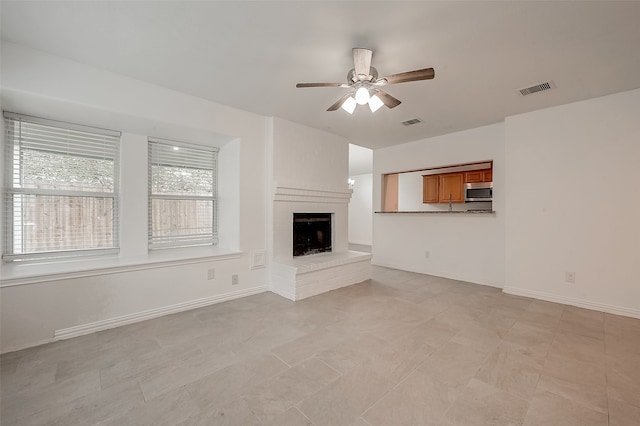 unfurnished living room with ceiling fan and a fireplace