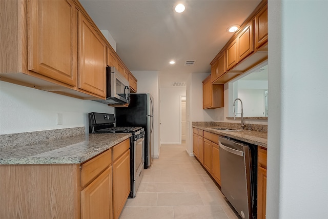 kitchen featuring light tile patterned flooring, stainless steel appliances, light stone counters, and sink