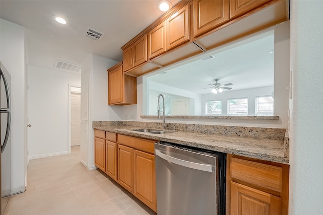 kitchen with stainless steel dishwasher, ceiling fan, light stone counters, and sink