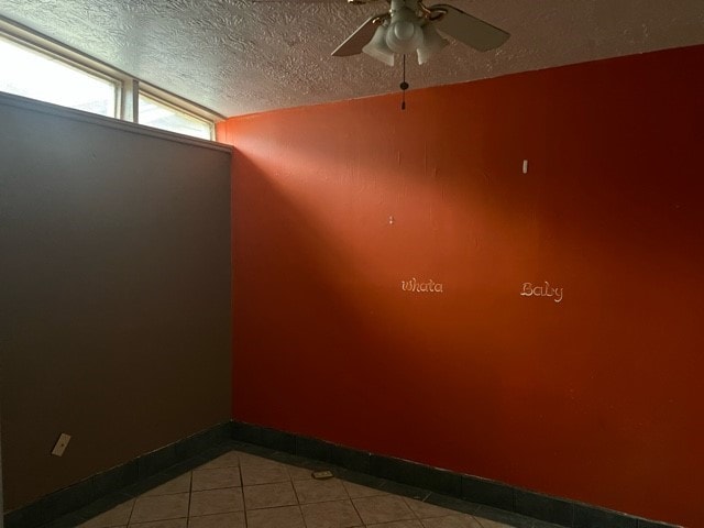 empty room featuring ceiling fan, a textured ceiling, and vaulted ceiling