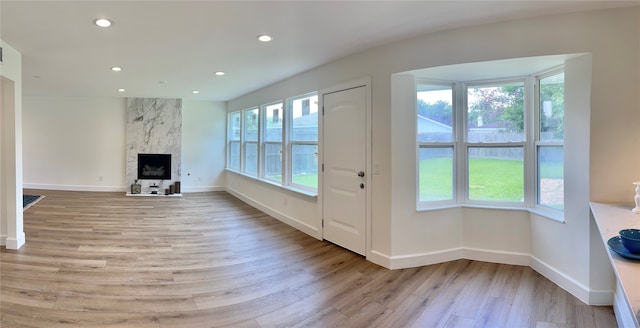 doorway to outside with light hardwood / wood-style floors, a healthy amount of sunlight, and a premium fireplace