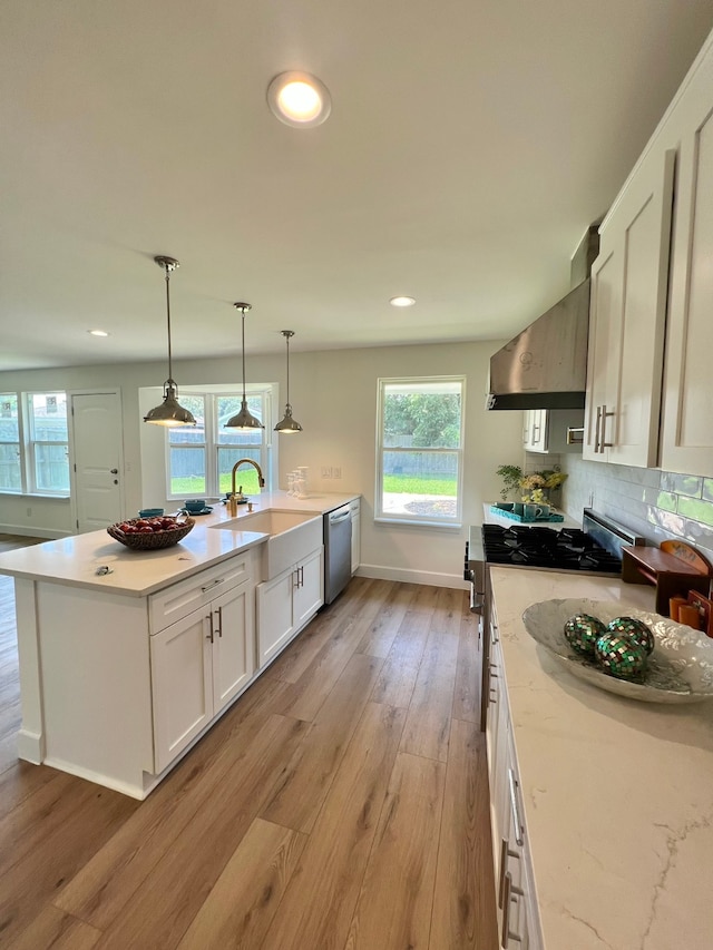 kitchen with plenty of natural light, light wood-type flooring, white cabinetry, and extractor fan