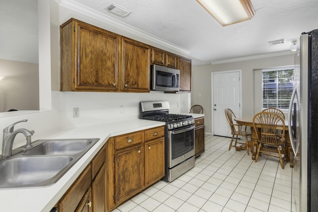 kitchen featuring crown molding, sink, light tile patterned floors, a textured ceiling, and stainless steel appliances