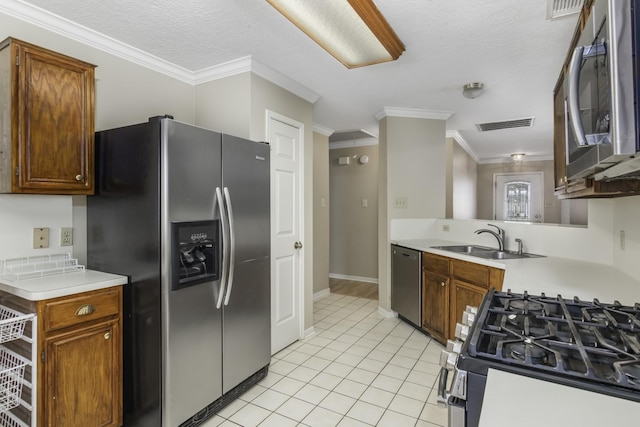 kitchen with appliances with stainless steel finishes, a textured ceiling, crown molding, sink, and light tile patterned flooring