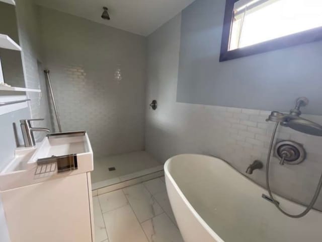 bathroom with vanity, independent shower and bath, and tile walls