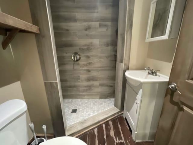 bathroom with vanity, toilet, and tiled shower