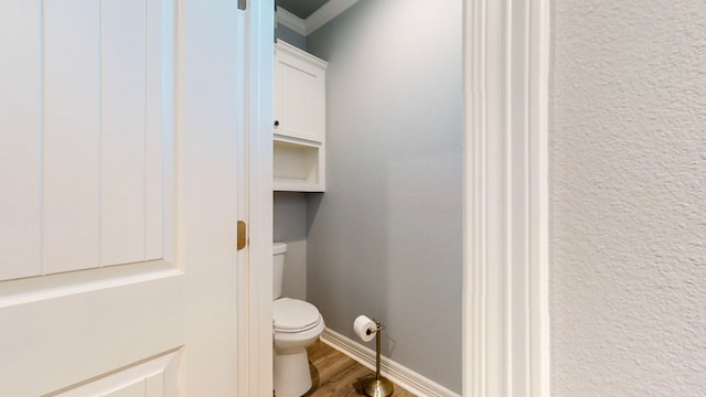 bathroom featuring hardwood / wood-style flooring, toilet, and ornamental molding