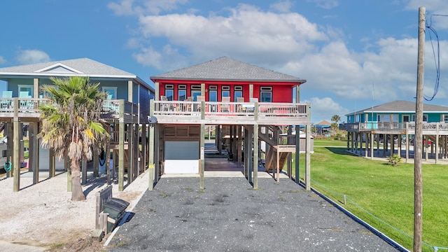 coastal home with a front yard, a carport, and a wooden deck