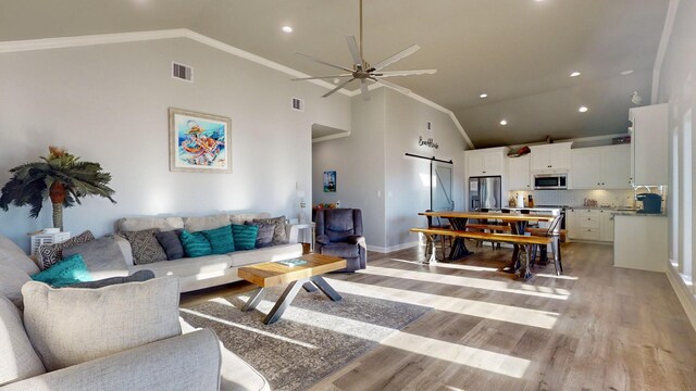 1819 Redfish Ln, Crystal Beach, TX 77650 - living area featuring a barn door, high vaulted ceiling, light wood-style flooring, ceiling fan, and ornamental molding