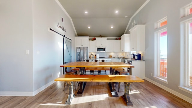 kitchen with white cabinets, a barn door, appliances with stainless steel finishes, and a wealth of natural light