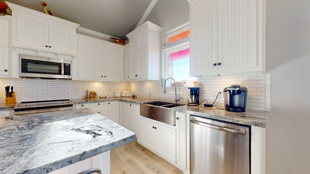 kitchen with white cabinetry, sink, stainless steel appliances, light hardwood / wood-style floors, and decorative backsplash