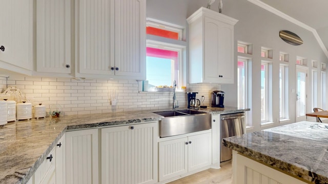 kitchen with dishwasher, white cabinets, sink, decorative backsplash, and light stone counters