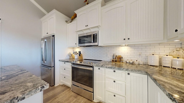 1819 Redfish Ln, Crystal Beach, TX 77650 - kitchen with stainless steel appliances, white cabinetry, light wood-style floors, light stone counters, and tasteful backsplash