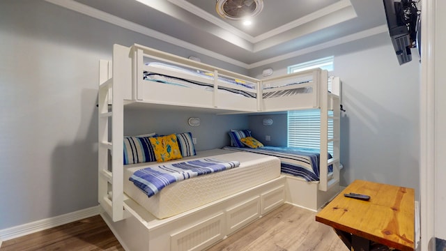 bedroom featuring a raised ceiling, light wood-type flooring, and ornamental molding