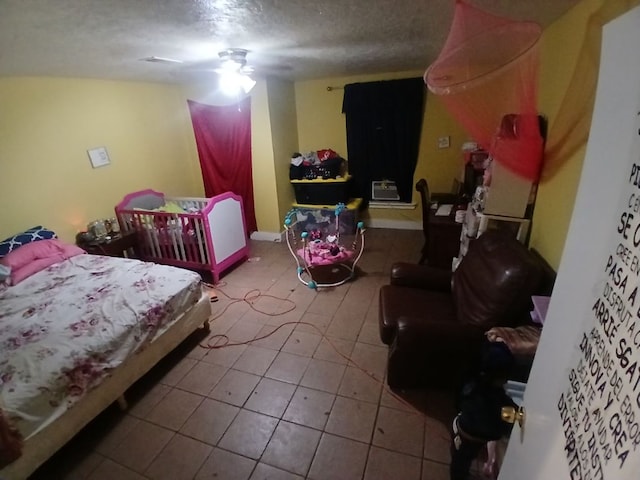 bedroom featuring ceiling fan, tile patterned flooring, and a textured ceiling