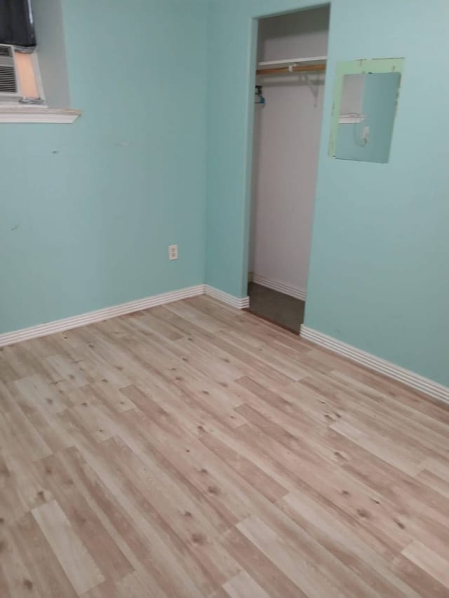 unfurnished bedroom with electric panel, light hardwood / wood-style floors, and a closet