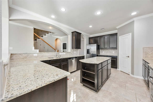 kitchen with light stone countertops, tasteful backsplash, kitchen peninsula, a kitchen island, and appliances with stainless steel finishes