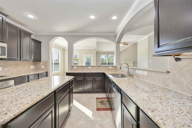 kitchen with decorative backsplash, light stone counters, dark brown cabinetry, stainless steel appliances, and sink