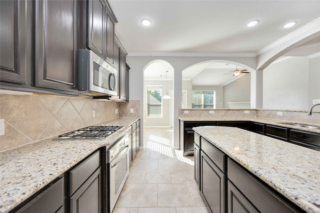 kitchen with sink, light stone countertops, stainless steel appliances, and tasteful backsplash