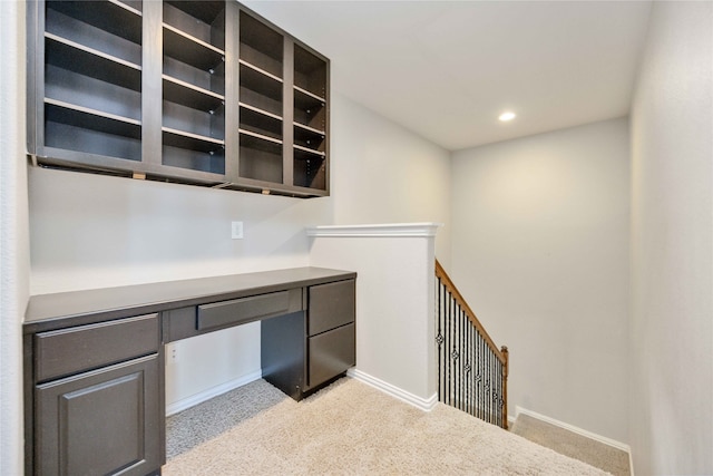 unfurnished office featuring built in desk and light carpet