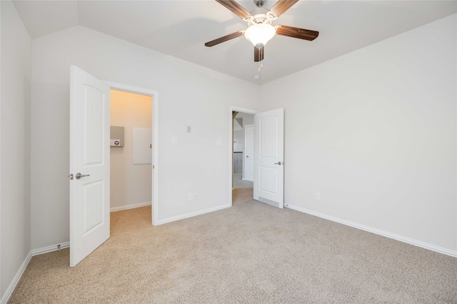 unfurnished bedroom with light carpet, a walk in closet, ceiling fan, and lofted ceiling