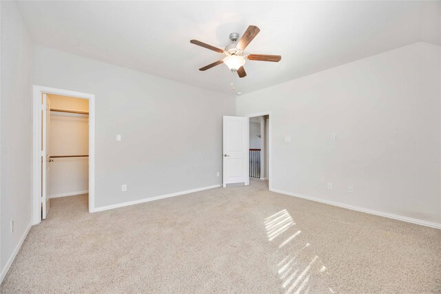 unfurnished bedroom with light carpet, vaulted ceiling, ceiling fan, a spacious closet, and a closet