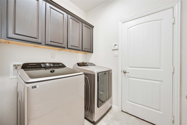 clothes washing area with cabinets and washer and dryer