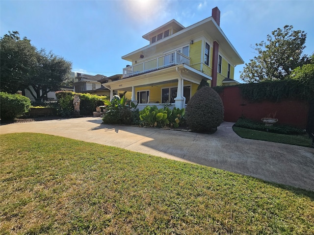 view of front of home featuring a porch, a balcony, and a front lawn