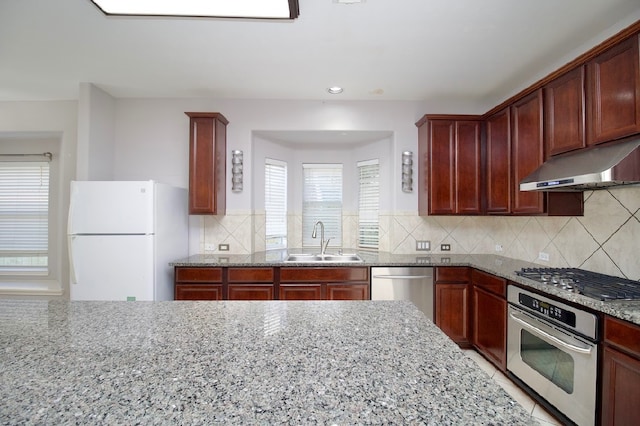 kitchen featuring tasteful backsplash, light stone counters, sink, and stainless steel appliances