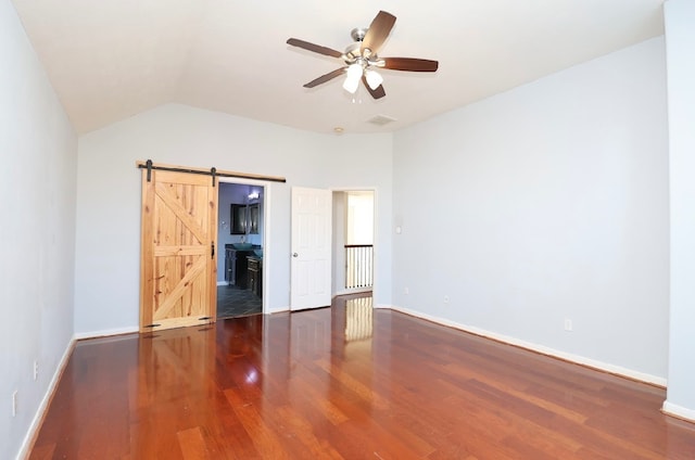 unfurnished bedroom featuring a barn door, ceiling fan, lofted ceiling, and hardwood / wood-style flooring