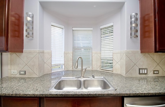 kitchen with dishwasher, sink, and light stone counters