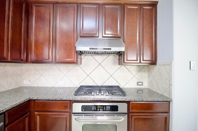 kitchen featuring appliances with stainless steel finishes, light stone counters, extractor fan, and tasteful backsplash