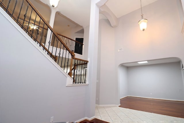 staircase with wood-type flooring and a towering ceiling