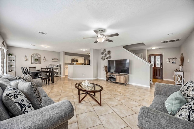 living room featuring light tile patterned floors, a textured ceiling, and ceiling fan