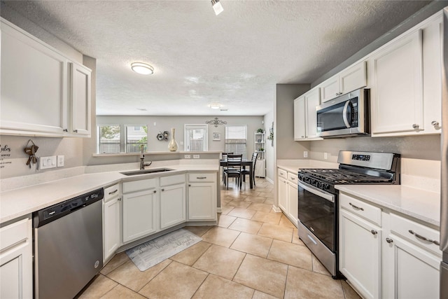 kitchen with white cabinets, appliances with stainless steel finishes, a textured ceiling, and sink