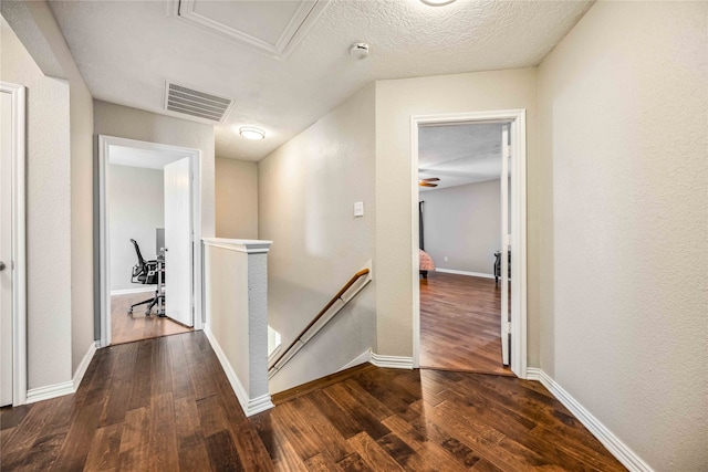 hall featuring dark wood-type flooring and a textured ceiling