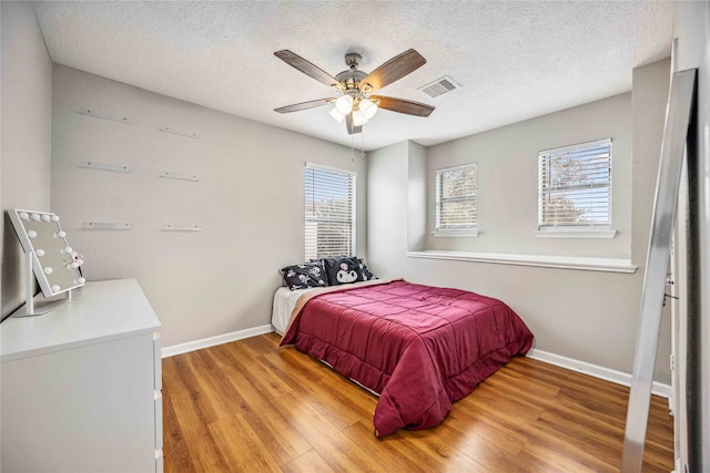 bedroom featuring a textured ceiling, light hardwood / wood-style floors, and ceiling fan