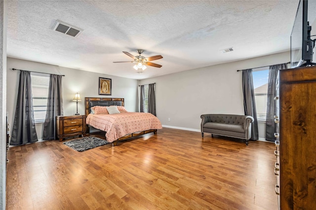 bedroom featuring hardwood / wood-style floors, ceiling fan, and a textured ceiling