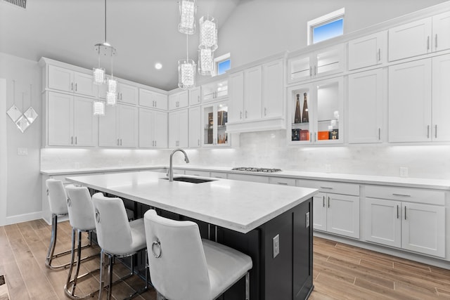 kitchen with a center island with sink, white cabinets, light hardwood / wood-style floors, and sink