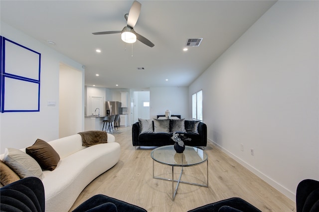 living room with ceiling fan, light hardwood / wood-style floors, and sink