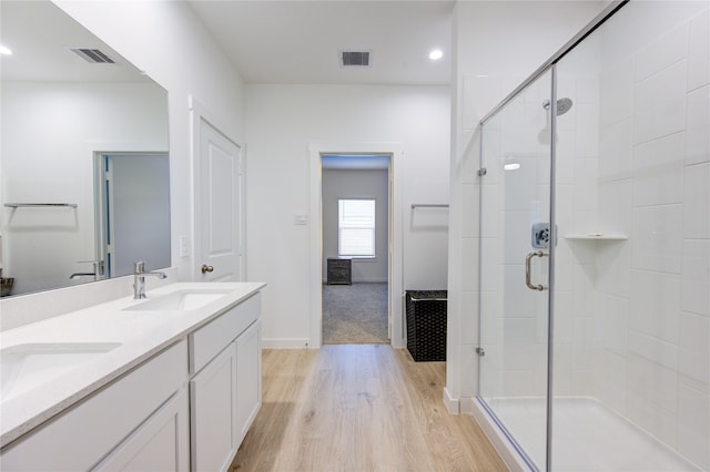 bathroom with hardwood / wood-style flooring, vanity, and a shower with shower door