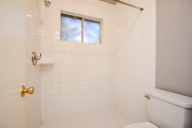 bathroom featuring toilet and a tile shower