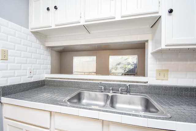 kitchen with decorative backsplash, white cabinets, and sink