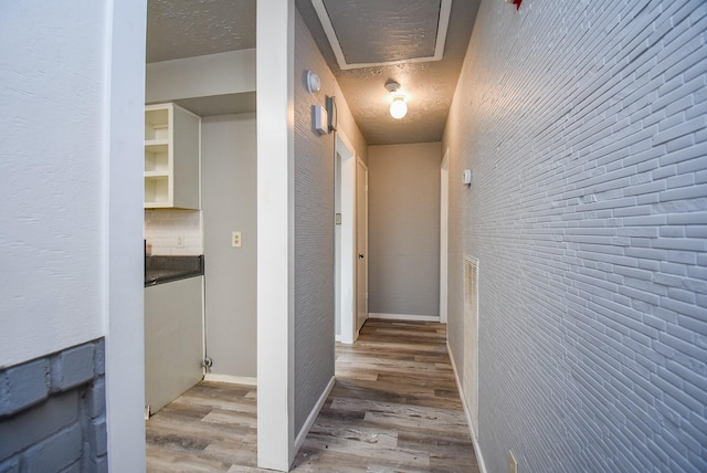 hall with hardwood / wood-style flooring and a textured ceiling