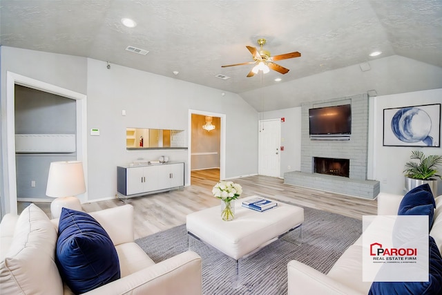 living room featuring lofted ceiling, ceiling fan, a brick fireplace, and light hardwood / wood-style flooring