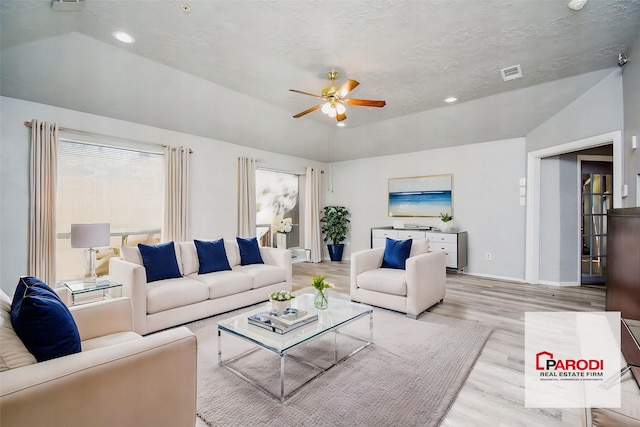 living room featuring light wood-type flooring, ceiling fan, lofted ceiling, and a textured ceiling