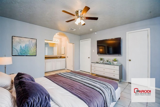 tiled bedroom featuring ceiling fan and connected bathroom