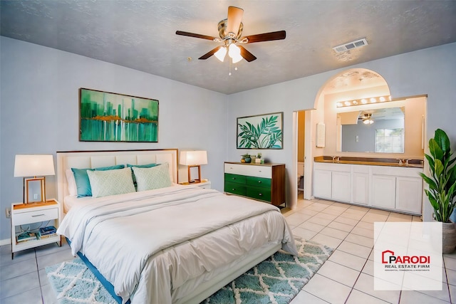 tiled bedroom featuring ceiling fan, sink, and ensuite bathroom