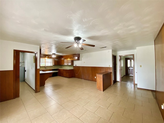 kitchen featuring kitchen peninsula, wooden walls, ceiling fan, and light tile patterned floors