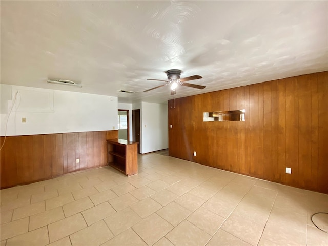 empty room with ceiling fan and wood walls